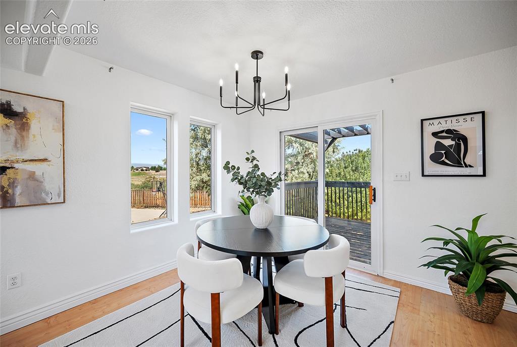 Image 6 of 40: Dining area featuring wood-finish flooring, white walls, and a contemporary