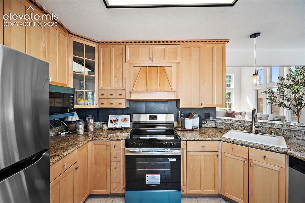 Image 9 of 40: Kitchen featuring wood cabinetry, stainless steel appliances, granite count