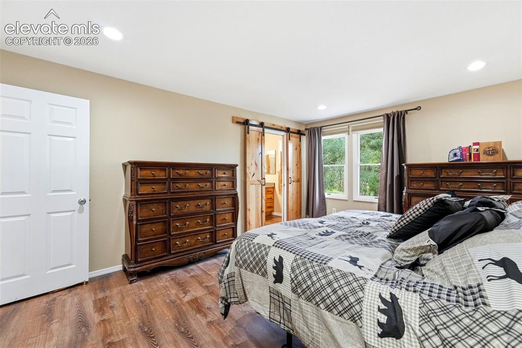 Image 12 of 42: Custom barn door leads to the remodeled 3/4 bath