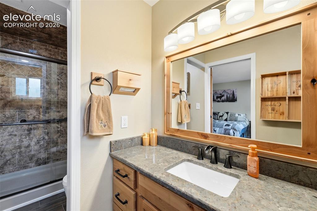 Image 13 of 42: Vanity with a rectangular sink, dark hardware, and a wood-framed mirror