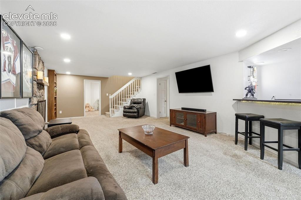 Image 31 of 42: Expansive carpeted recreation room featuring a stone-clad fireplace, built-