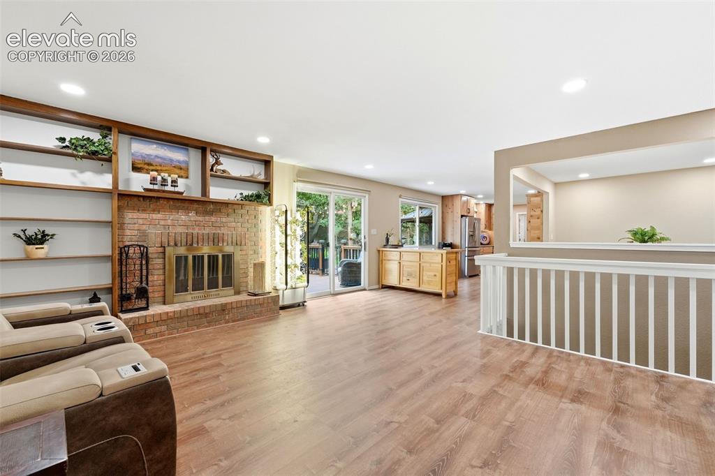 Image 5 of 42: Brick wood burning fireplace with built-ins open to the kitchen