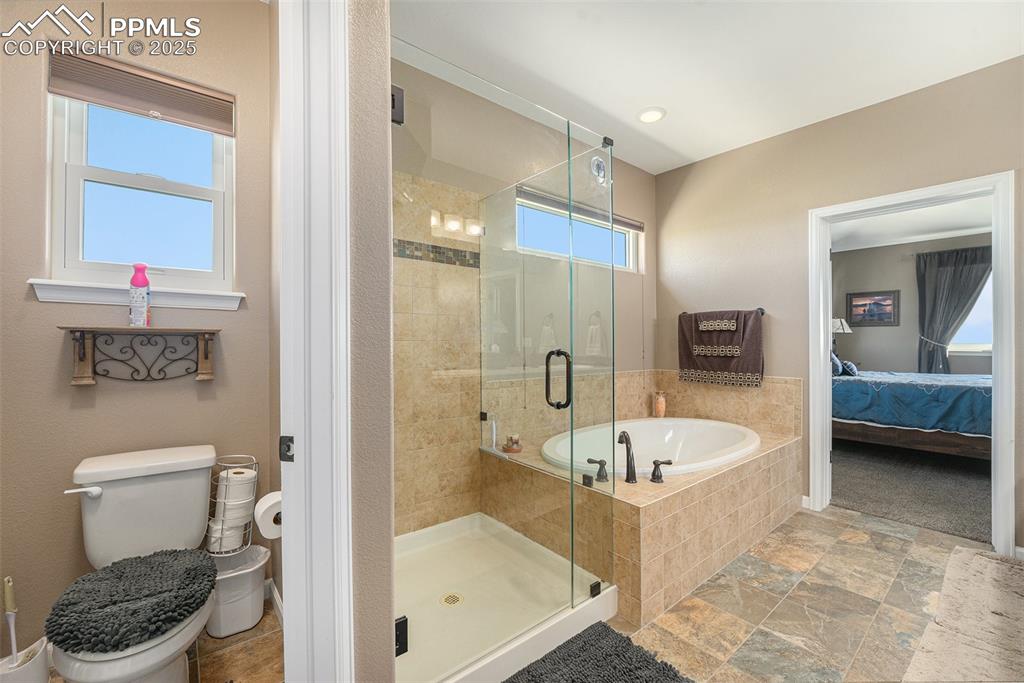 Image 16 of 48: Bathroom with a garden tub, ensuite bathroom, a stall shower, and stone fin