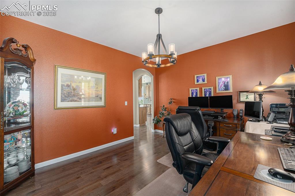 Image 17 of 48: Office area featuring arched walkways, dark wood-style flooring, and a chan