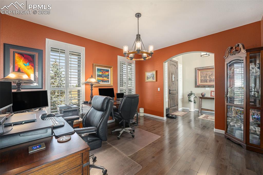 Image 18 of 48: Office area featuring dark wood-style floors, a chandelier, and arched walk