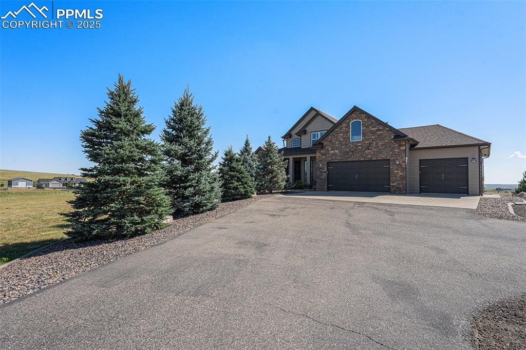 Image 2 of 48: View of front of house featuring stone siding, asphalt driveway, and an att