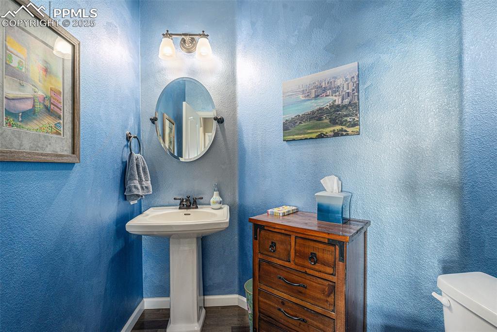 Image 20 of 48: Bathroom with a textured wall and dark wood-type flooring
