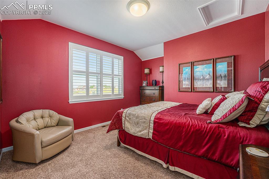Image 22 of 48: Bedroom with lofted ceiling, attic access, carpet flooring, and a textured 