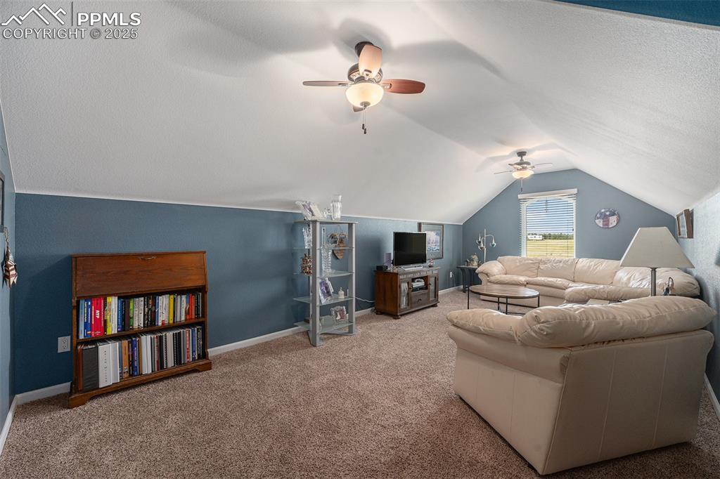 Image 24 of 48: Living room featuring vaulted ceiling, carpet floors, and ceiling fan