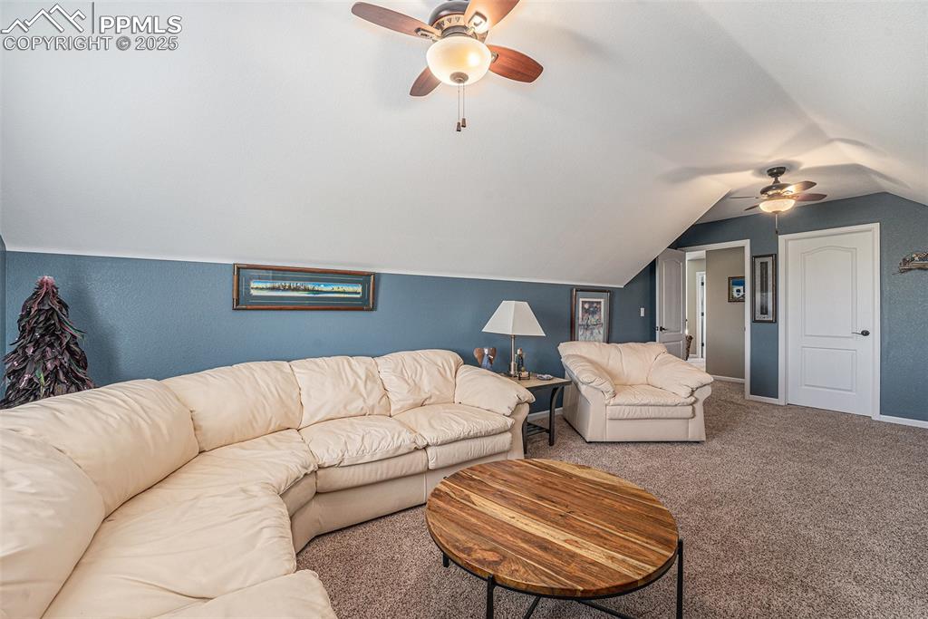 Image 25 of 48: Carpeted living area featuring ceiling fan and vaulted ceiling