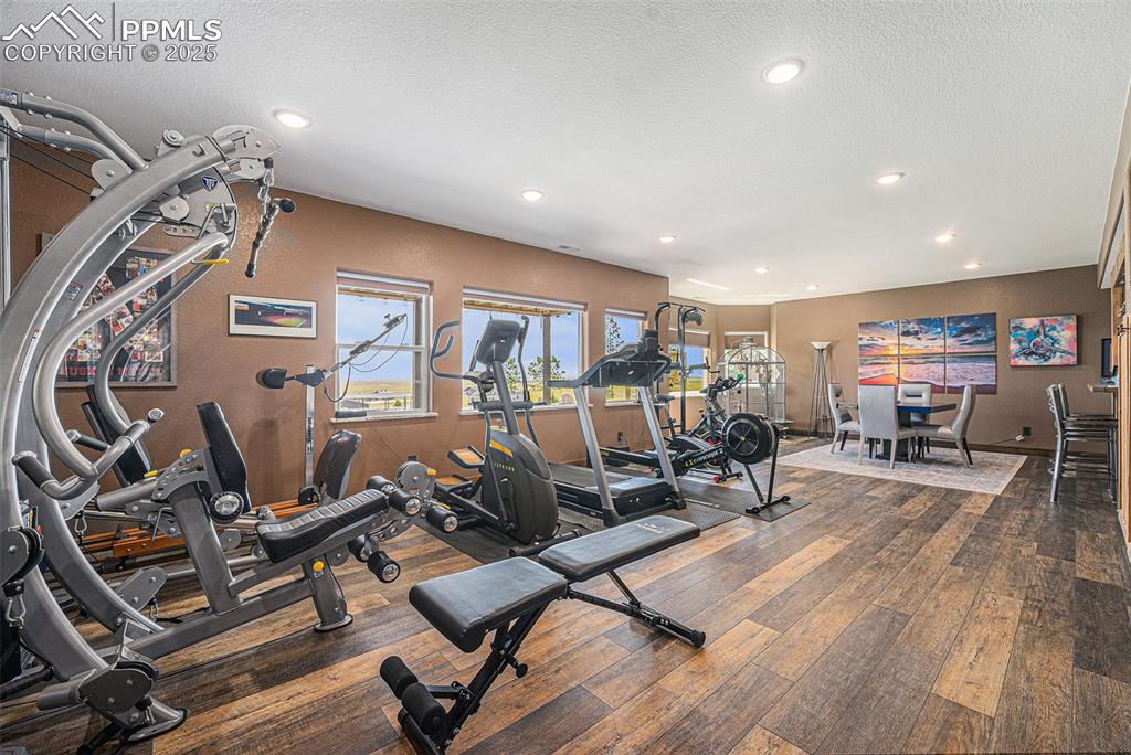 Image 26 of 48: Gym with a textured ceiling, recessed lighting, and hardwood / wood-style f