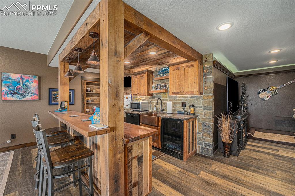 Image 30 of 48: Indoor wet bar featuring a textured wall, butcher block counters, beverage 