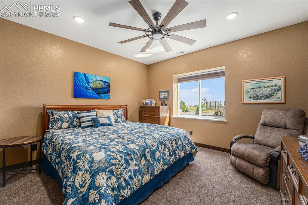 Image 33 of 48: Carpeted bedroom with a textured wall, a ceiling fan, and recessed lighting