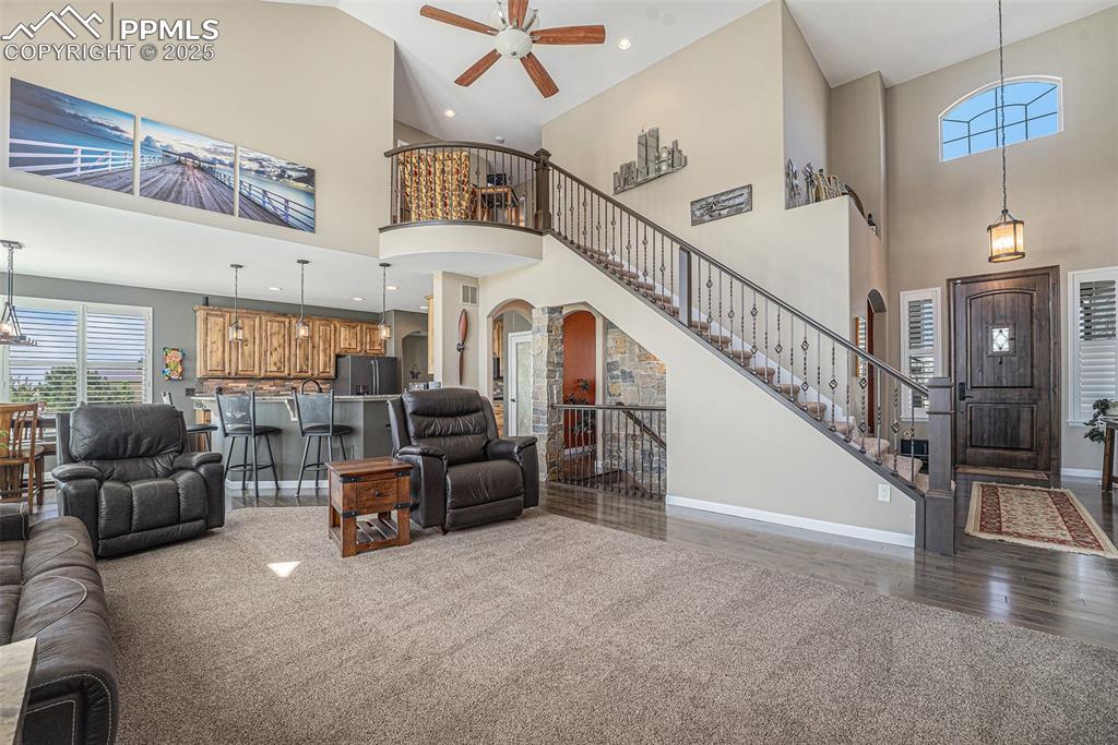 Image 4 of 48: Living room with arched walkways, a high ceiling, light colored carpet, sta