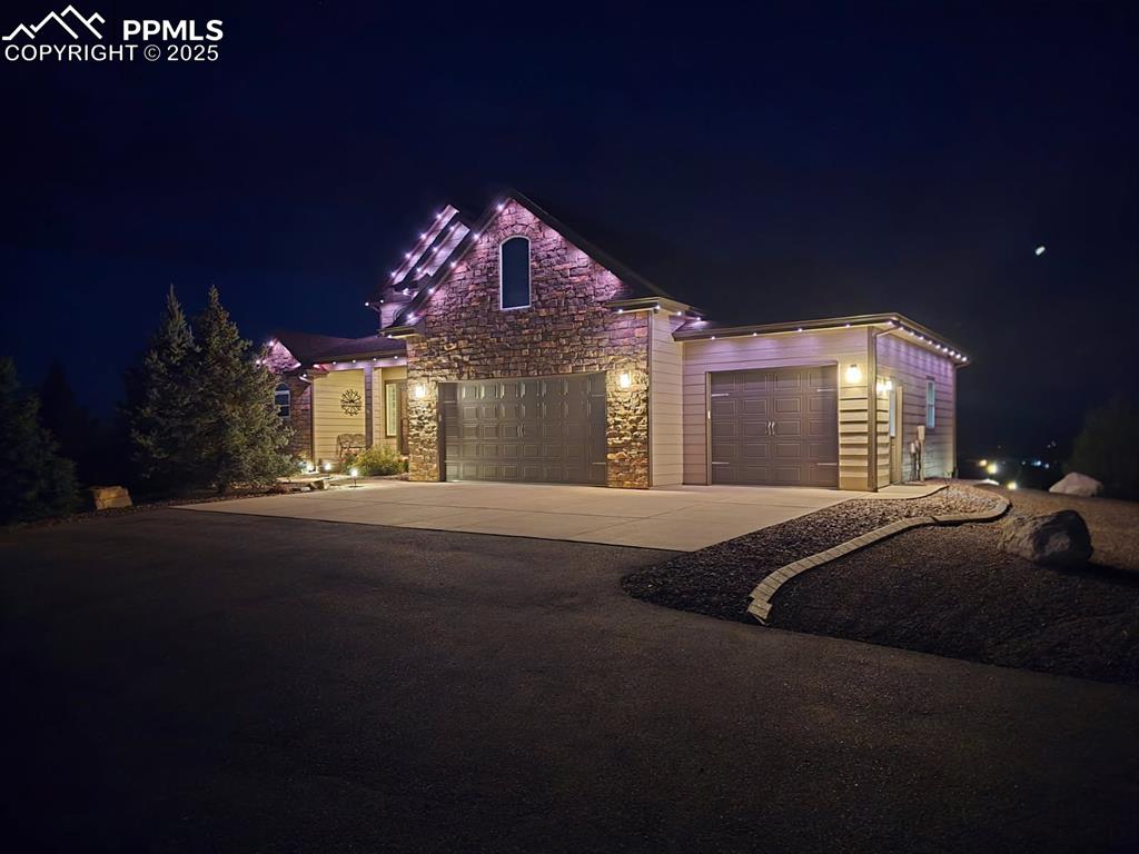Image 46 of 48: View of front facade featuring driveway, a garage, and stone siding