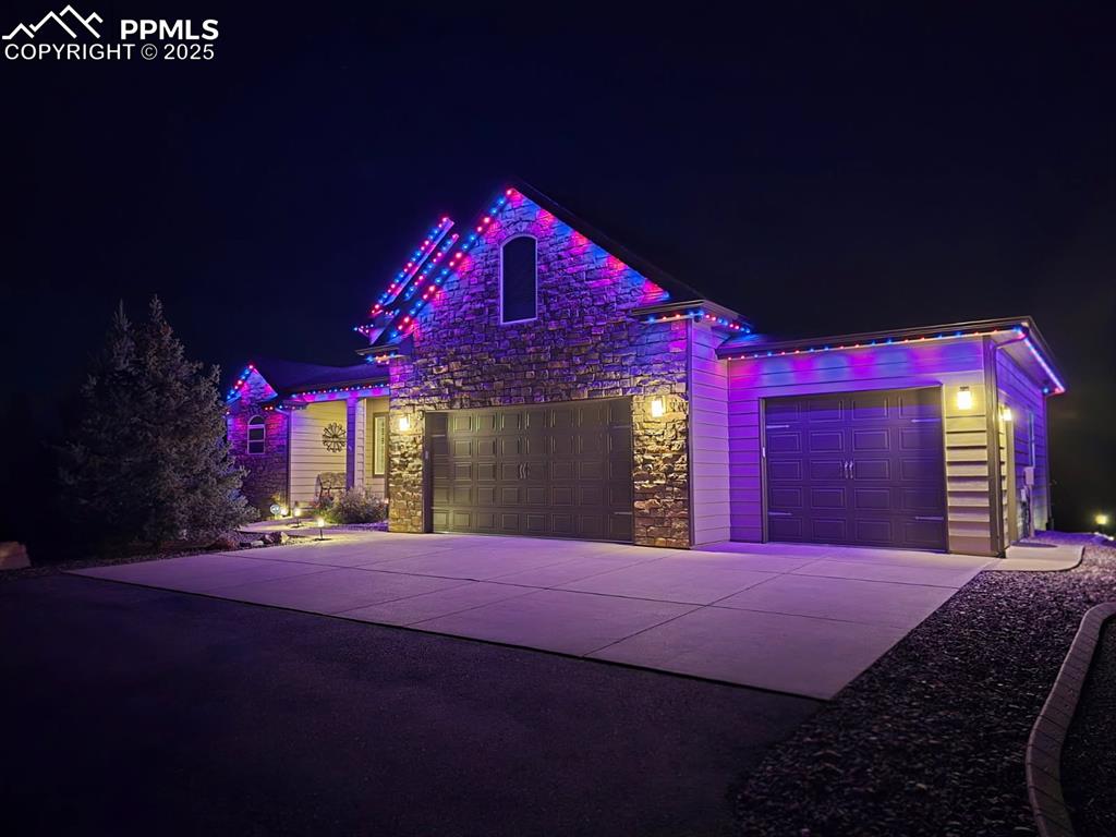 Image 47 of 48: View of front of house with a garage, stone siding, and concrete driveway