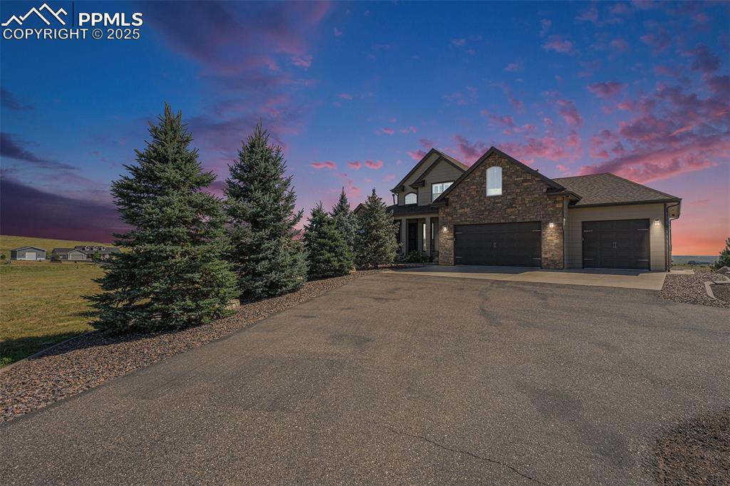 Image 48 of 48: View of front of home with stone siding, driveway, and a garage