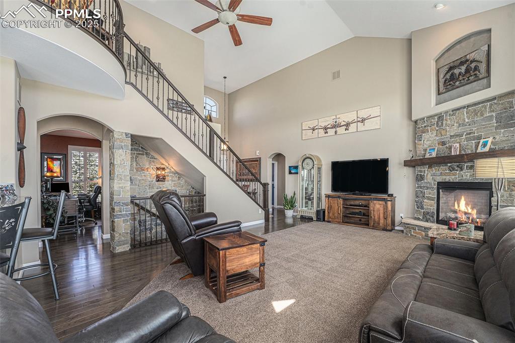 Image 5 of 48: Living room featuring arched walkways, a stone fireplace, dark wood-style f