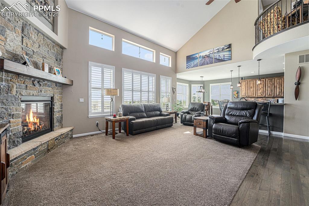 Image 6 of 48: Living room with high vaulted ceiling, a stone fireplace, plenty of natural