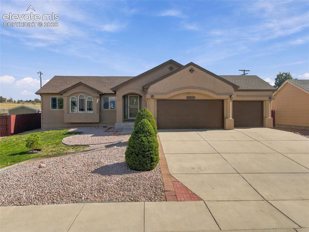 Caption: Stucco exterior with a shingle roof, arched entryway, and multiple garage bays