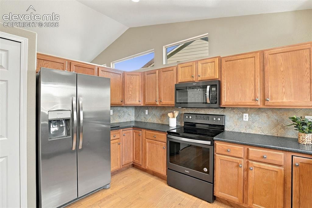Image 10 of 50: Kitchen featuring stainless steel refrigerator, black range, black microwav