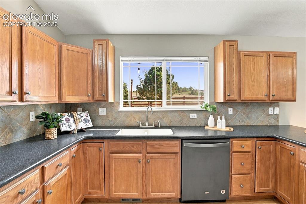 Image 12 of 50: Wood-finish cabinetry with silver-tone hardware, dark countertops, a large