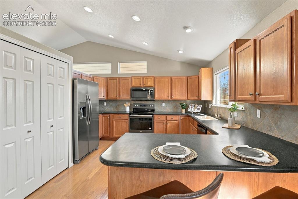 Image 13 of 50: Kitchen featuring wood cabinetry, stainless steel appliances, dark countert