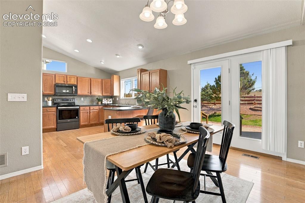 Image 16 of 50: Kitchen with wood-finish flooring, wood cabinetry, and a dark stone-finish