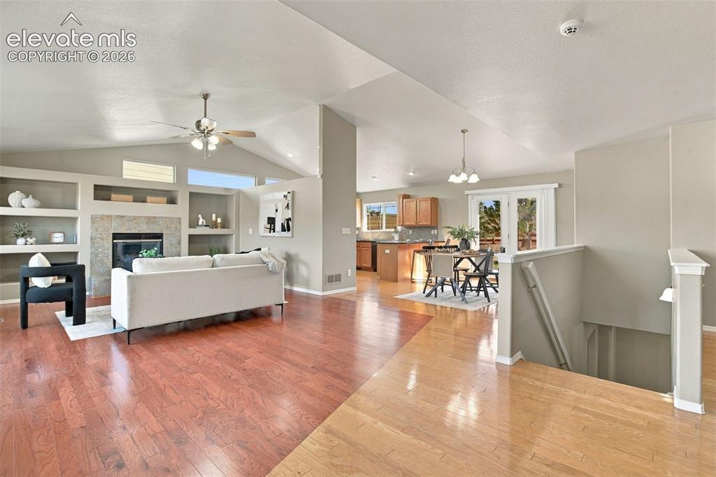Image 2 of 50: Vaulted ceilings with a ceiling fan, built-in shelving, a fireplace with st