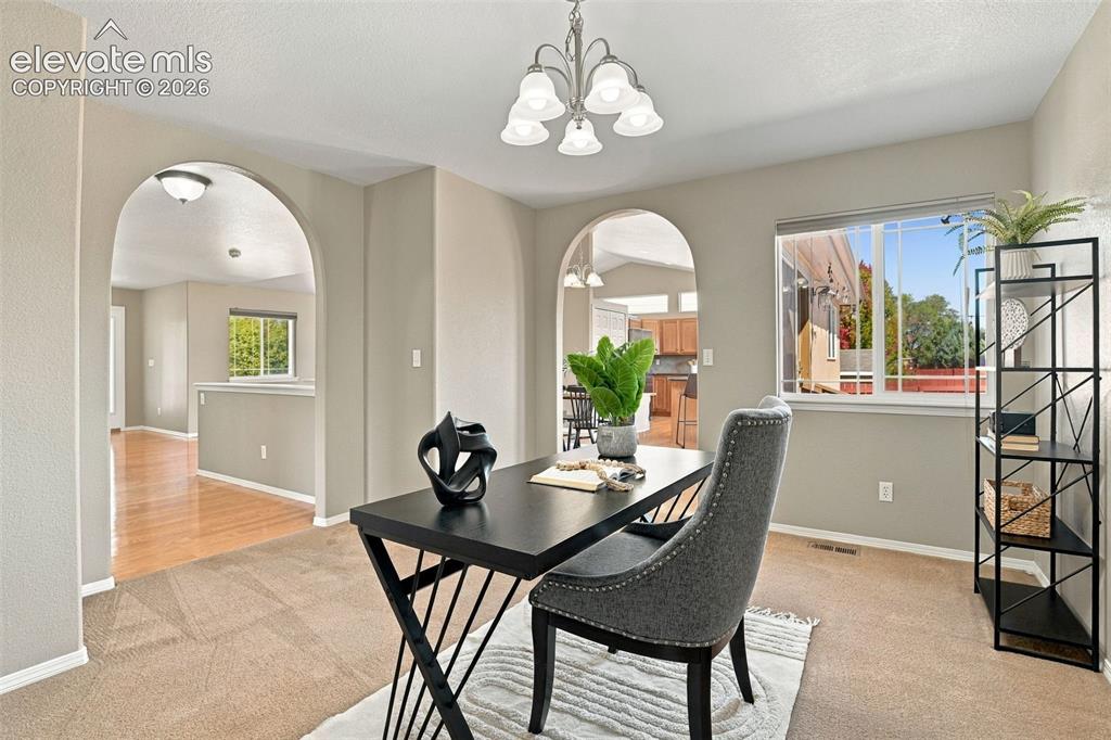 Image 21 of 50: Spacious room featuring multiple arched doorways, a large window, and a cha