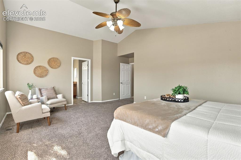 Image 25 of 50: Vaulted ceiling with a ceiling fan, neutral wall tones, and carpet flooring