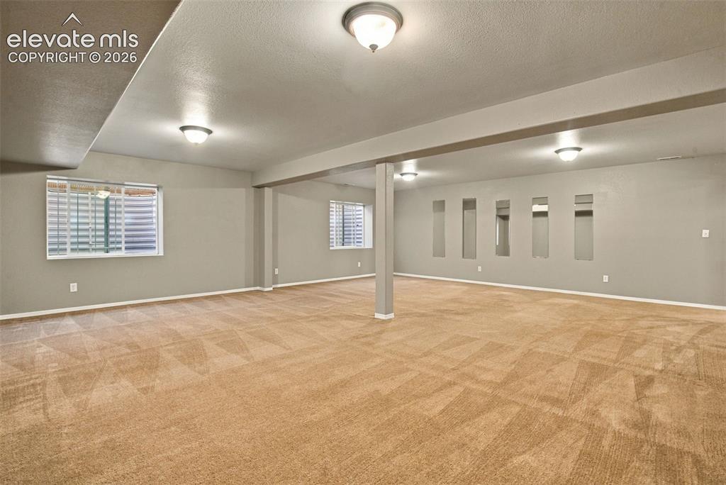 Image 34 of 50: Spacious room featuring carpeting, recessed wall niches, multiple windows w