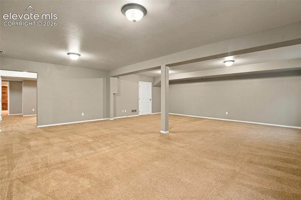 Image 35 of 50: Expansive carpeted area with neutral wall paint, recessed lighting, and whi