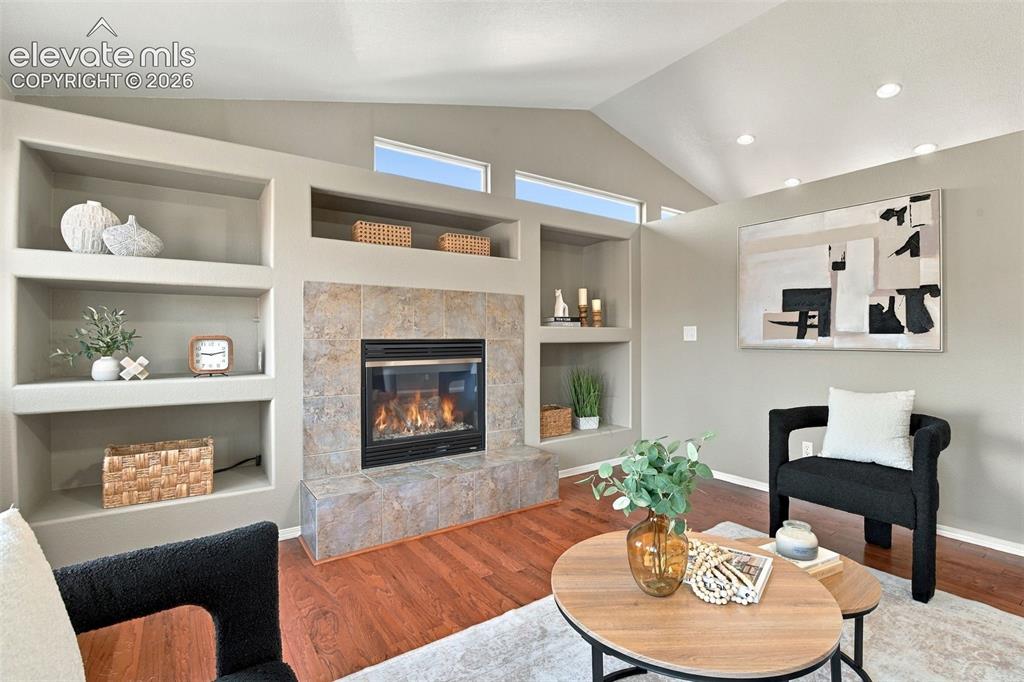 Image 4 of 50: Living area featuring a fireplace with a stone tile surround, built-in shel