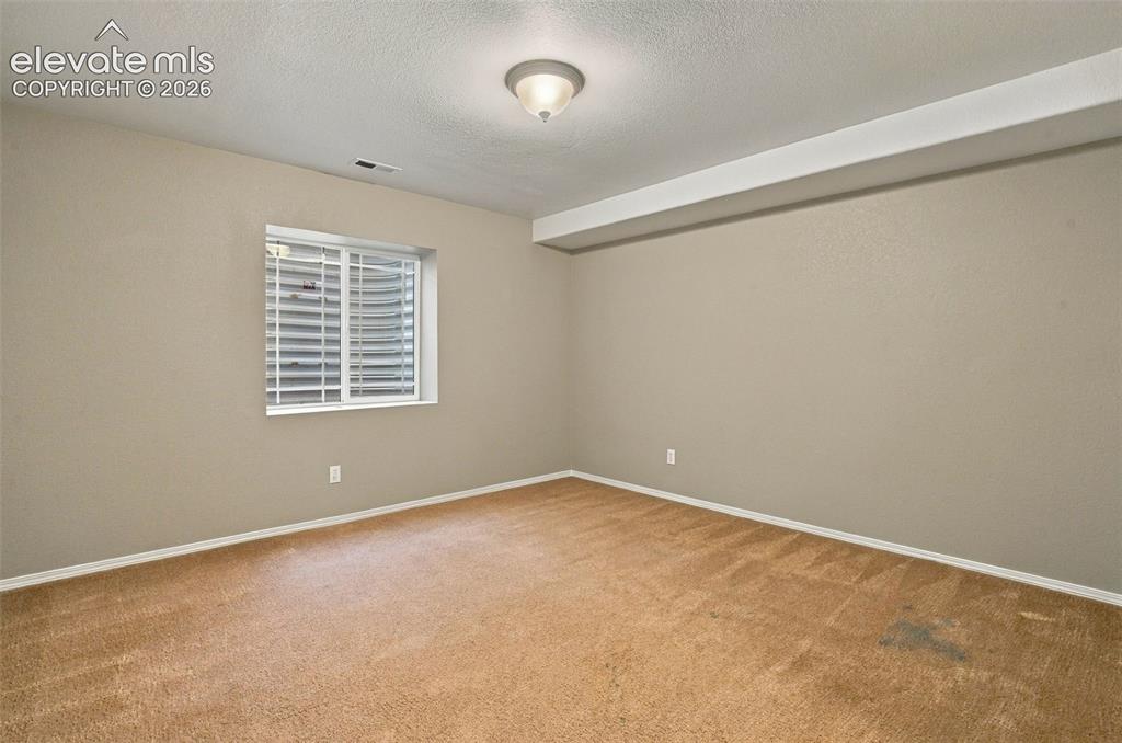 Image 41 of 50: Carpeted room with a single window featuring horizontal blinds and a flush-
