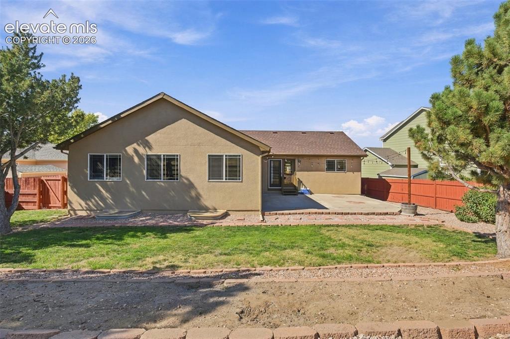 Image 45 of 50: Expansive backyard featuring a concrete patio, mature trees, and a wooden p