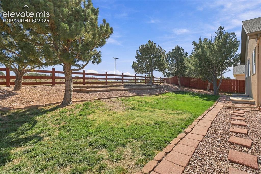 Image 46 of 50: Expansive tiered backyard featuring a grass lawn, mature trees, a red wood