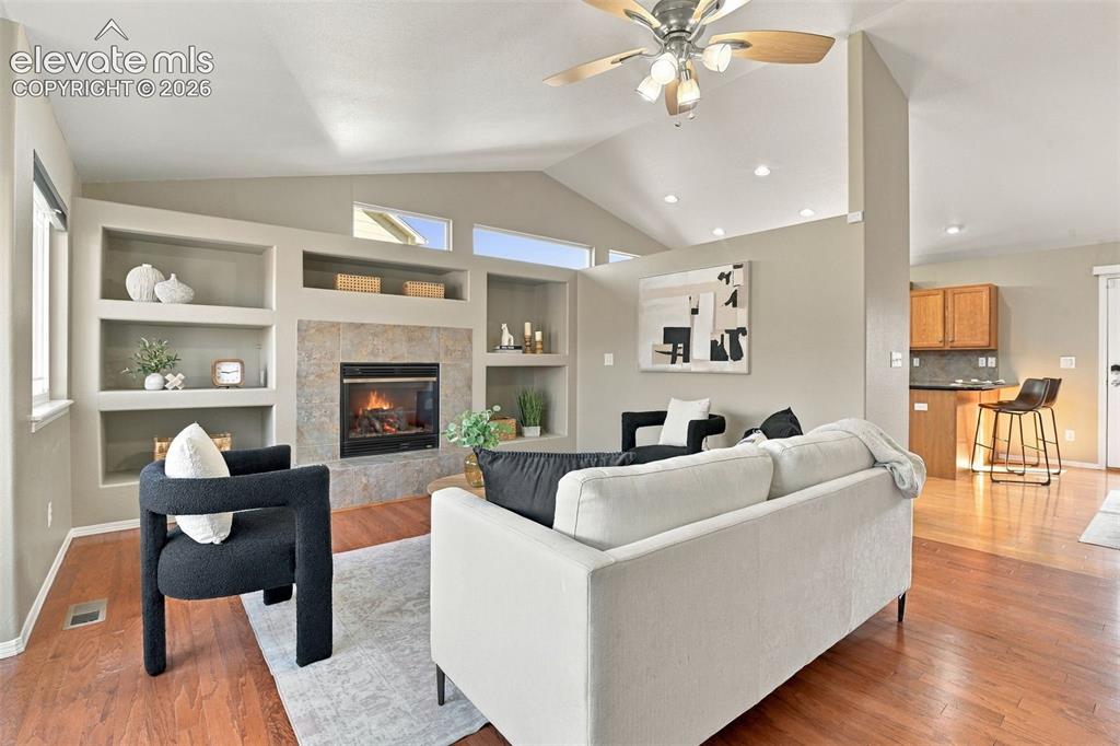 Image 5 of 50: Vaulted ceiling, wood-finish flooring, built-in shelving, tiled fireplace, 