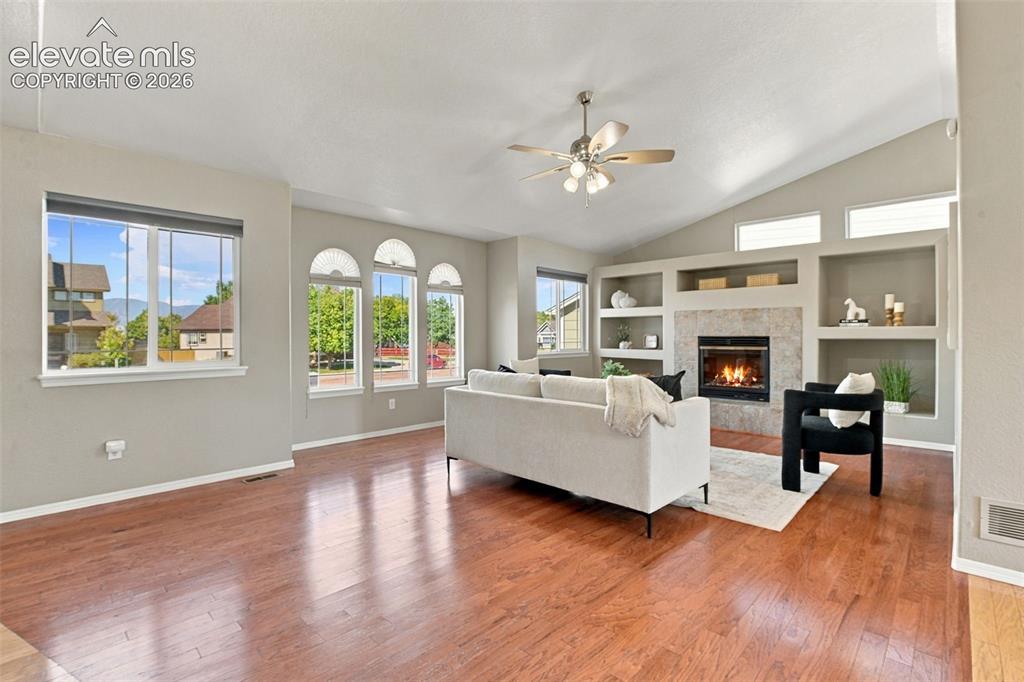 Image 8 of 50: Vaulted ceiling with a ceiling fan, recessed built-in shelving, stone-surro