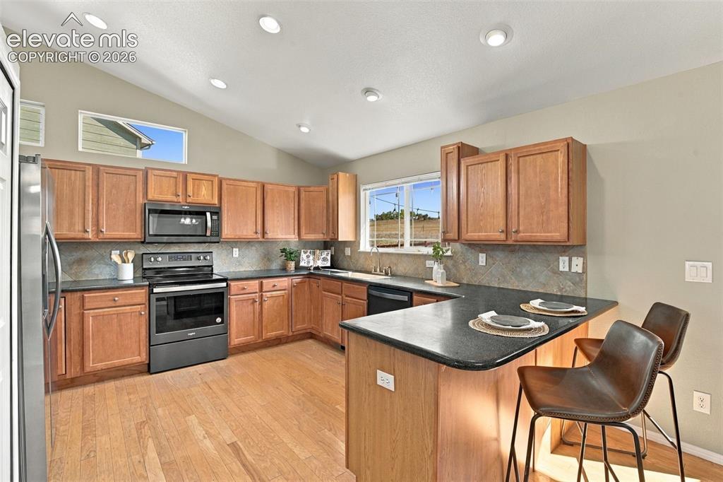 Image 9 of 50: Kitchen with wood-finish flooring, recessed lighting, vaulted ceiling, wood