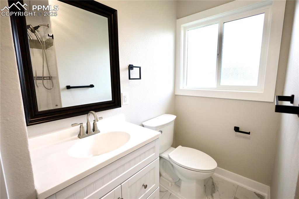 Image 12 of 27: Bathroom with vanity, a tile shower, and marble look tile flooring