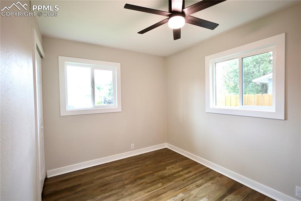 Image 20 of 27: Spare room with dark wood finished floors and a ceiling fan