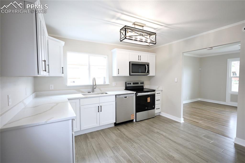 Image 8 of 27: Kitchen with appliances with stainless steel finishes, white cabinets, crow