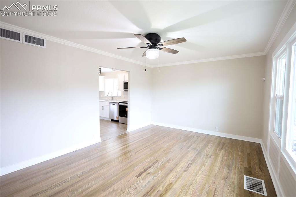 Image 9 of 27: Unfurnished room with ornamental molding, light wood-style flooring, and ce