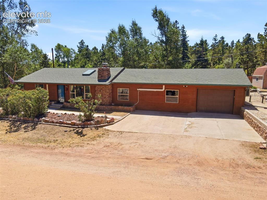 Caption: Ranch-style residence featuring a stone-clad chimney, a skylight, and an attached garage with a conc