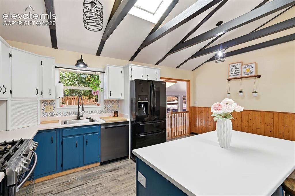 Image 10 of 50: Vaulted ceiling with exposed beams, skylight, wood-finish flooring, white u