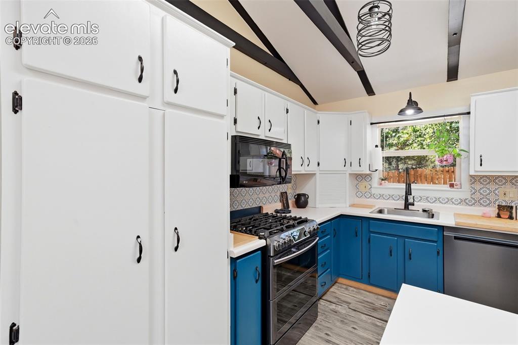 Image 11 of 50: Kitchen featuring white upper cabinetry, blue lower cabinetry, and exposed 
