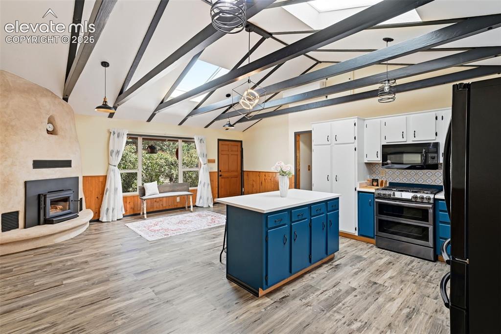 Image 12 of 50: Open-concept living space with vaulted ceilings featuring exposed beams and