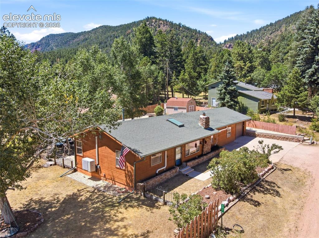 Image 2 of 50: Ranch-style residence featuring natural wood siding and a stone chimney