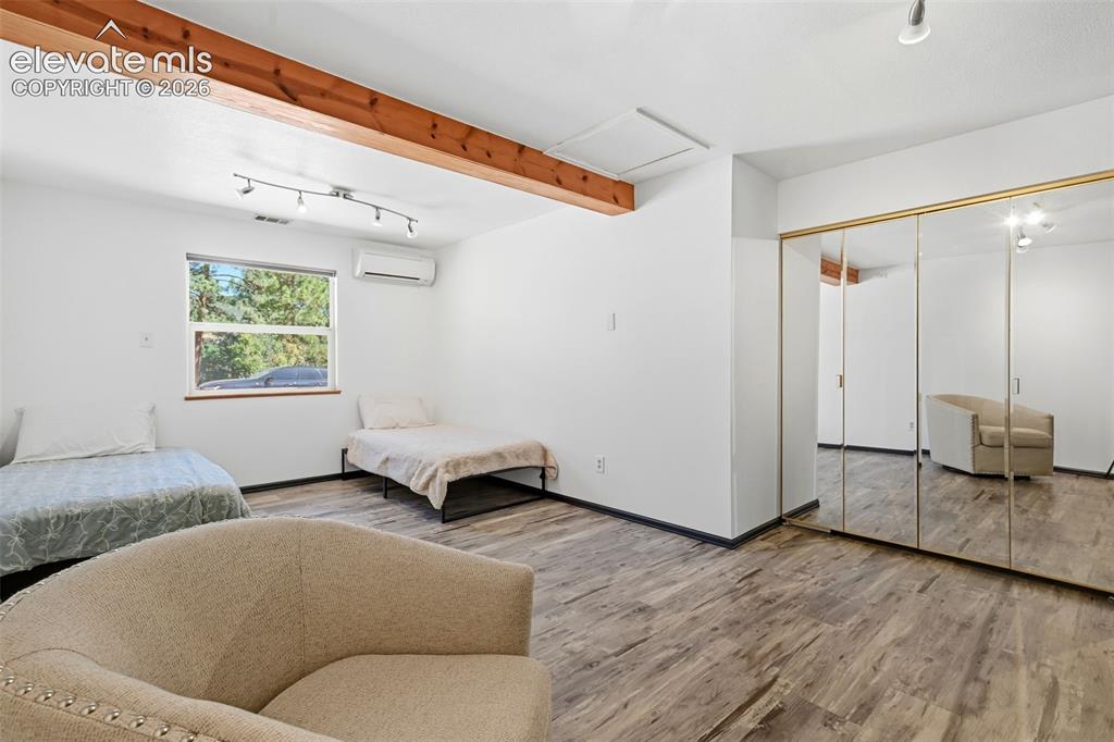 Image 22 of 50: Room featuring wood-finish flooring, exposed wood beam, large window, track
